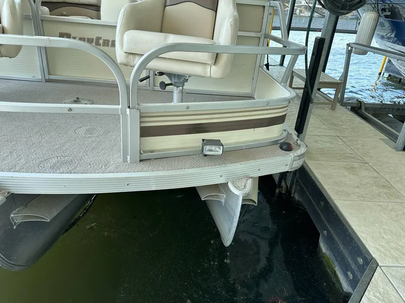 Slide: The Image of 2004 PlayCraft 2500 Ultra pontoon boat docked, featuring beige seating and metal railings. - 24