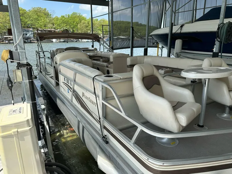 Slide: The Image of 2004 PlayCraft 2500 Ultra pontoon boat docked in a marina, featuring spacious seating and table. - 26