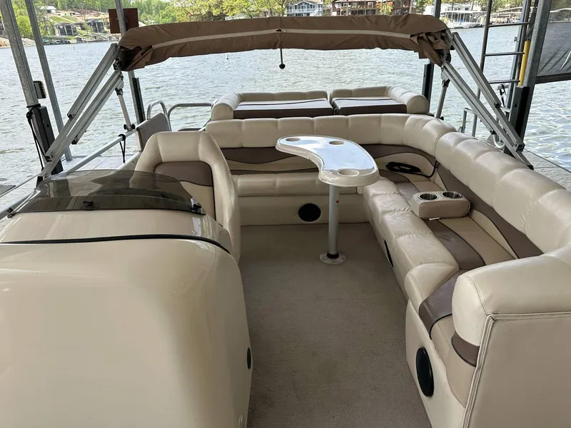 Slide: The Image of 2004 PlayCraft 2500 Ultra pontoon boat interior with seating and table, docked by the water. - 33