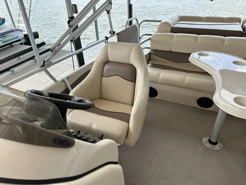 Slide: The Image of 2004 PlayCraft 2500 Ultra pontoon boat interior with beige seating and steering console. - 7
