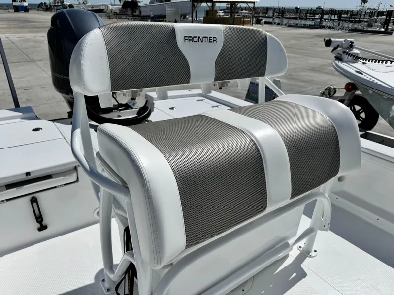 Slide: The Image of 2025 Frontier 2104 boat seat with gray and white upholstery, docked at marina. - 16