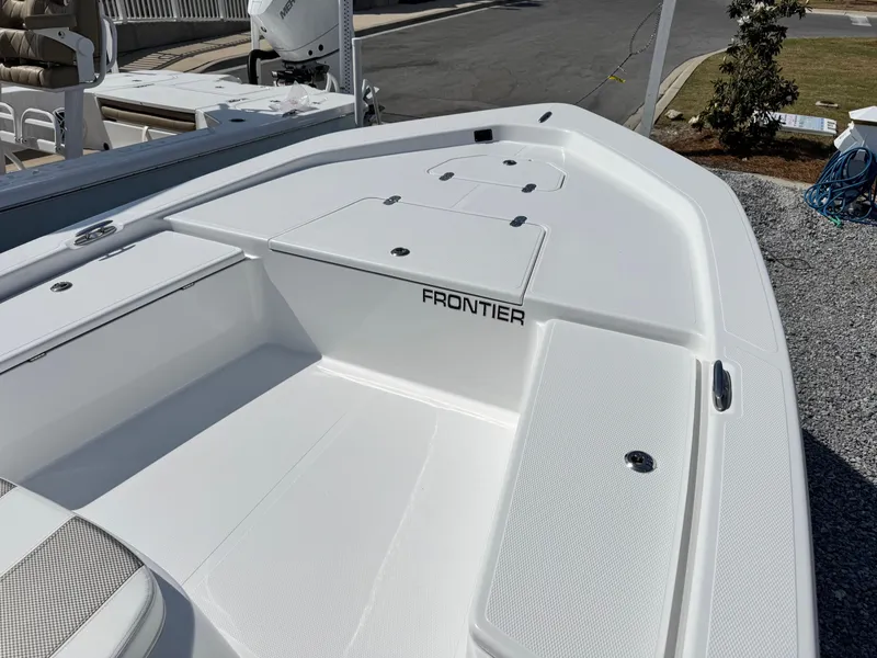 Slide: The Image of 2025 Frontier 2104 boat deck, white with storage compartments, parked on gravel. - 6
