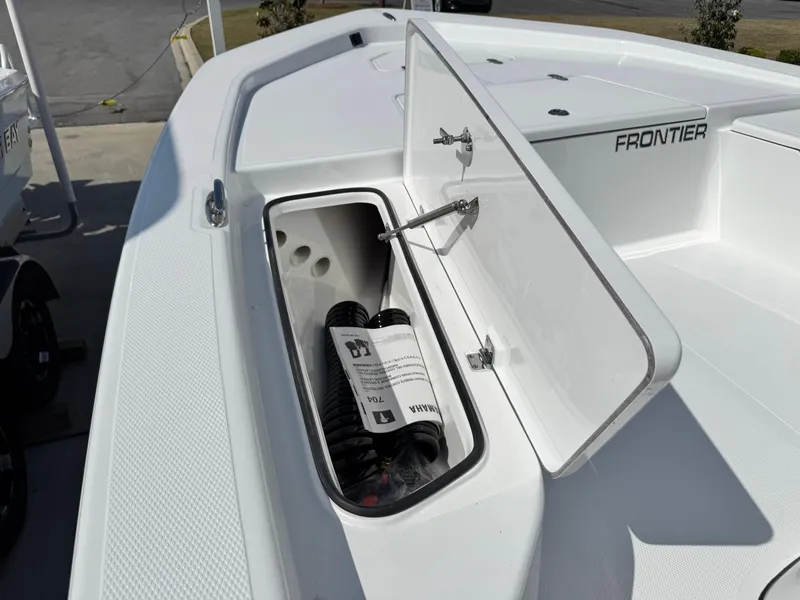 Slide: The Image of Open storage compartment on 2025 Frontier 2104 boat deck, showing coiled rope and manual. - 9