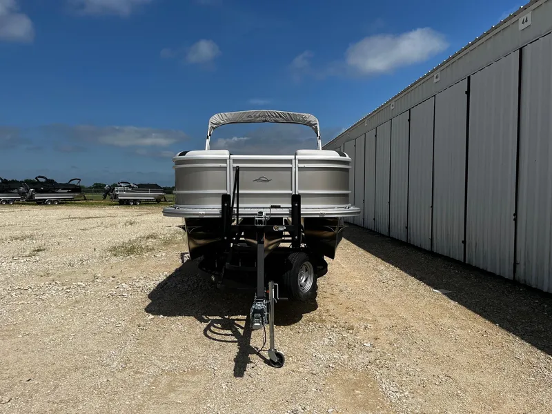 Slide: The Image of 2025 SunCatcher Select 324SL pontoon boat parked outdoors near storage units. - 2