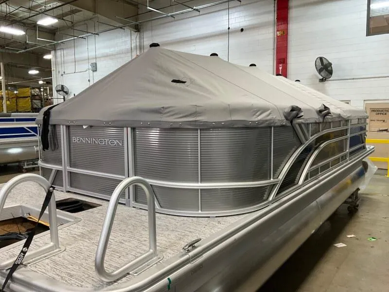 Slide: The Image of 2025 Bennington 23SSR-SPS pontoon boat with cover in a warehouse setting. - 5