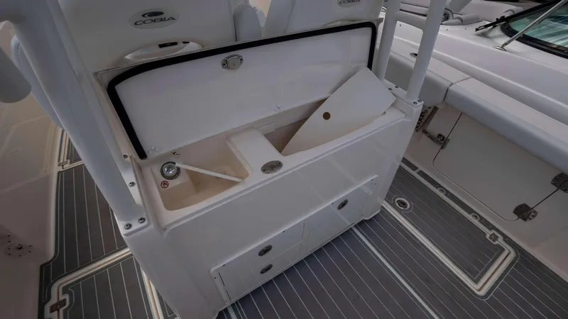 Slide: The Image of 2021 Cobia 301 CC boat interior storage compartment with open lid and seating area. - 11