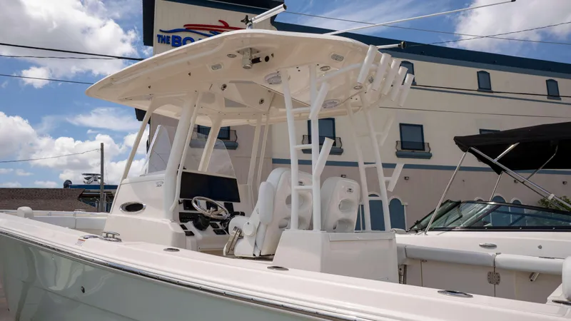 Slide: The Image of 2021 Cobia 301 CC boat with T-top, docked near a building under a blue sky. - 13