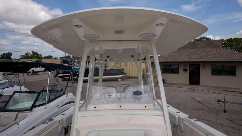 Slide: The Image of 2021 Cobia 301 CC boat with T-top, docked at a marina under a clear sky. - 4