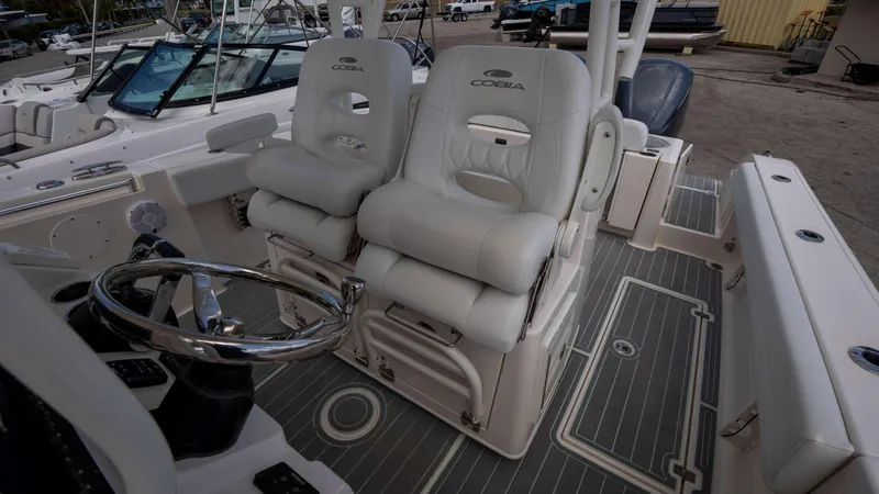 Slide: The Image of 2021 Cobia 301 CC boat interior with dual captain's chairs and steering wheel. - 7