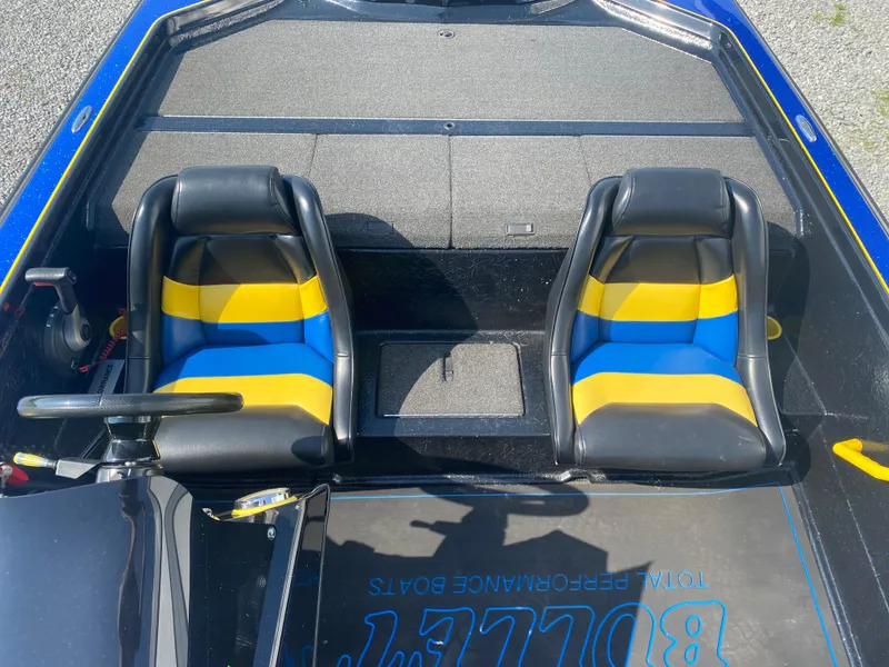 Slide: The Image of 2013 Bullet 21XRD boat interior with blue and yellow seats, steering wheel, and carpet branding. - 12