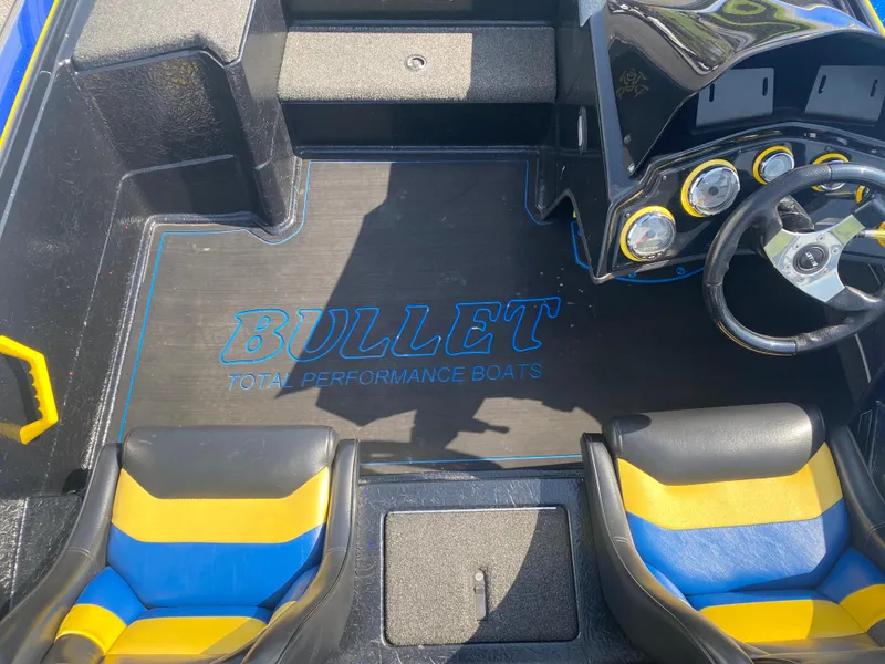 Slide: The Image of 2013 Bullet 21XRD boat interior with blue and yellow seats and dashboard gauges. - 8