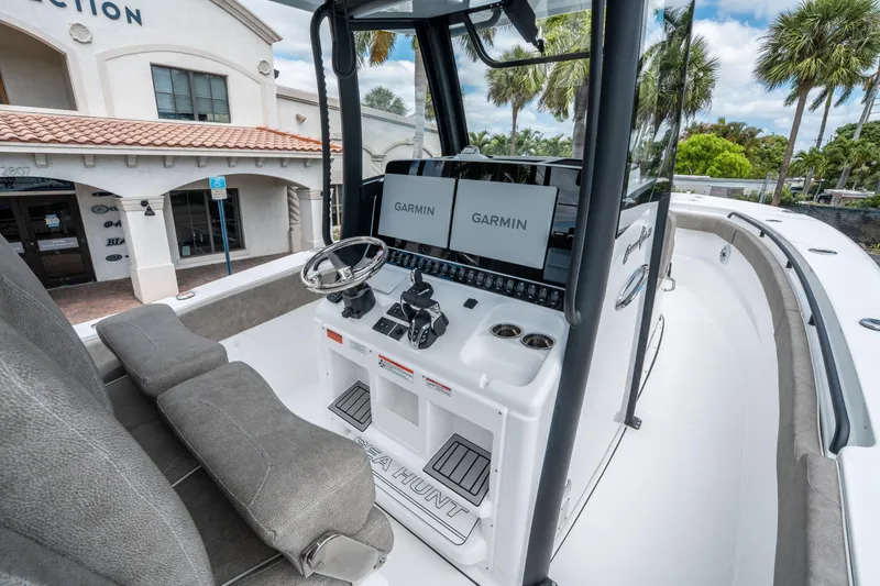 Slide: The Image of 2025 Sea Hunt Gamefish 28 CB boat console with Garmin displays, docked near a building. - 18
