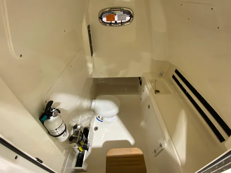 Slide: The Image of 2023 Boston Whaler 330 Outrage cabin interior with toilet and fire extinguisher. - 12