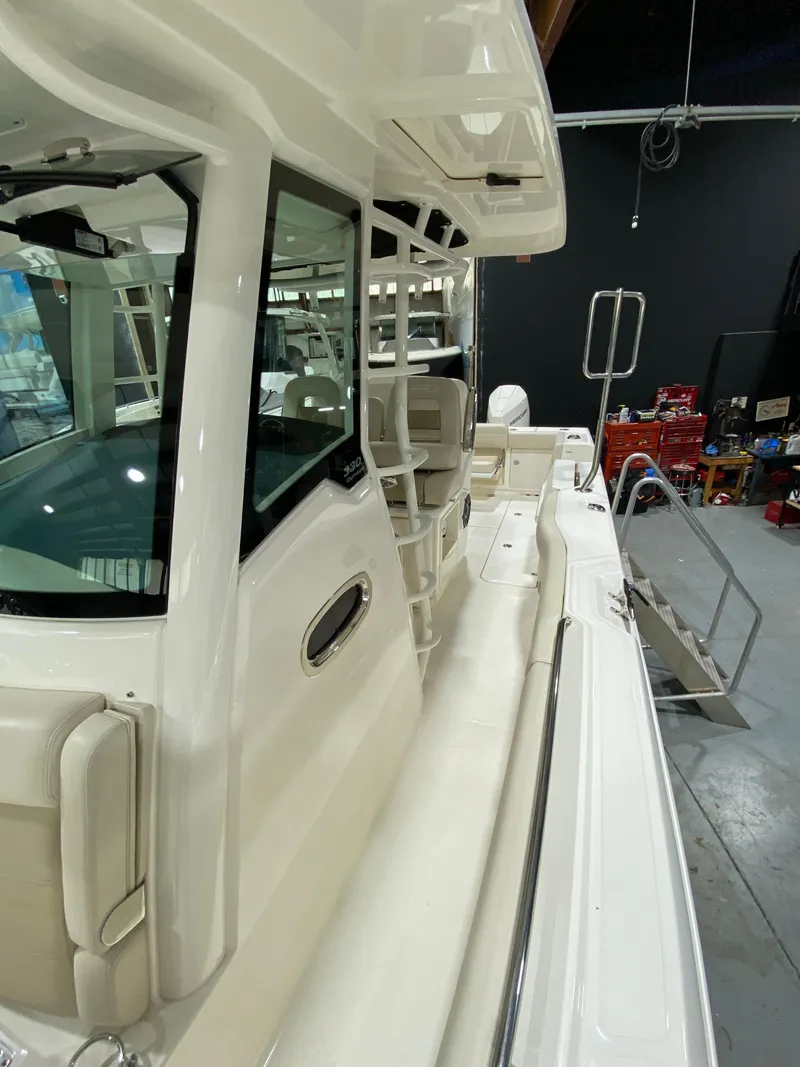 Slide: The Image of 2023 Boston Whaler 330 Outrage boat, side view in a showroom setting. - 15