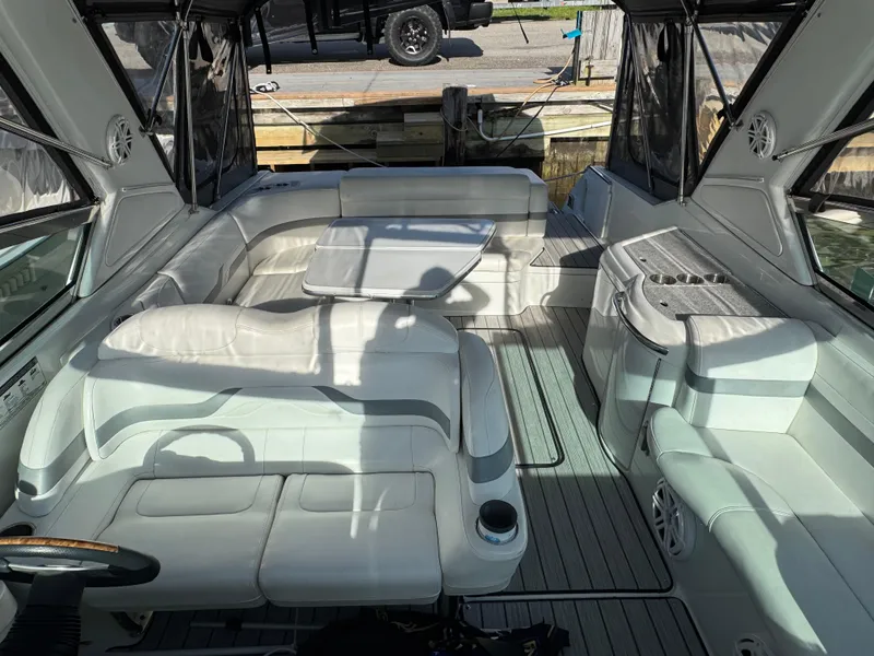 Slide: The Image of 2007 Formula 330 SS boat interior with white seating and table, docked near a truck. - 18