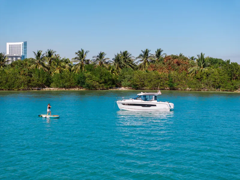 Slide: The Image of 2025 Jeanneau NC895 S2 boat on turquoise water near lush tropical shoreline. - 5