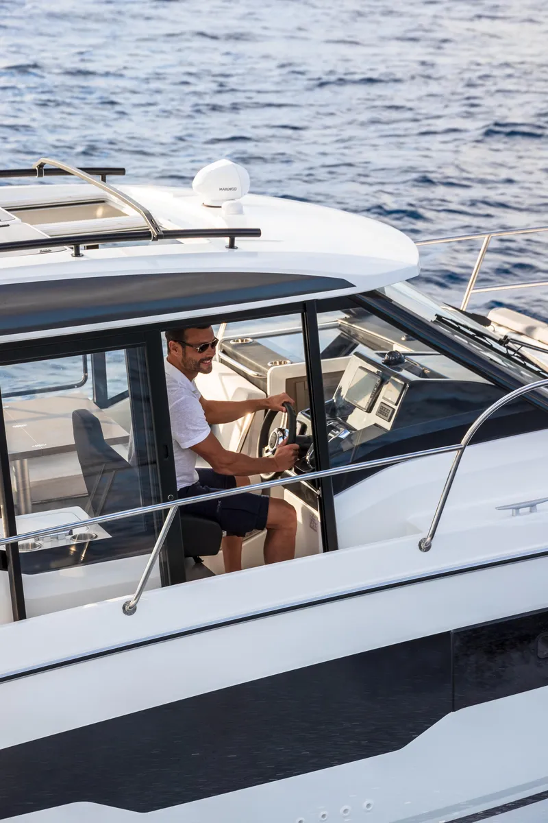 Slide: The Image of 2025 Jeanneau NC895 S2 boat cruising on open water with a person at the helm. - 6