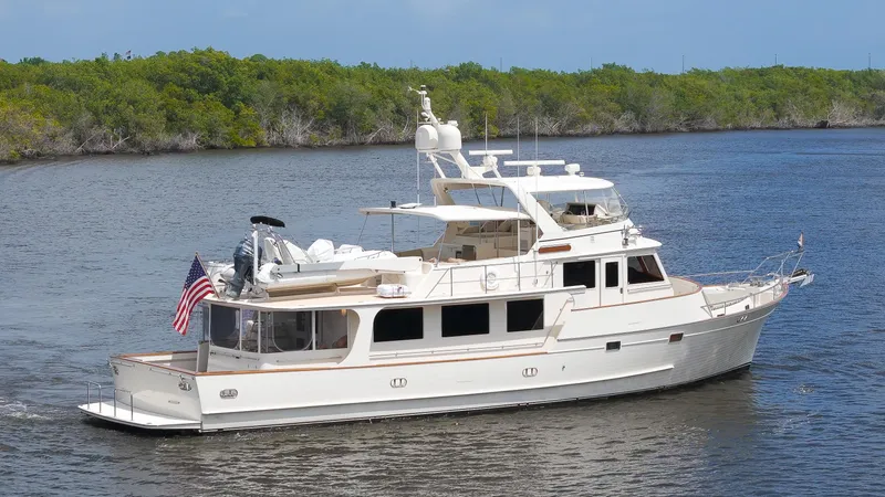 The Image of Luxurious 2006 Fleming 75 yacht cruising on a serene waterway with lush greenery. - 0