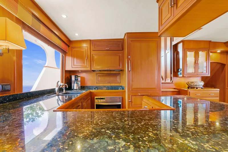 Slide: The Image of Luxurious kitchen interior on a 2006 Fleming 75 yacht, featuring elegant wood cabinetry and granite countertops. - 11