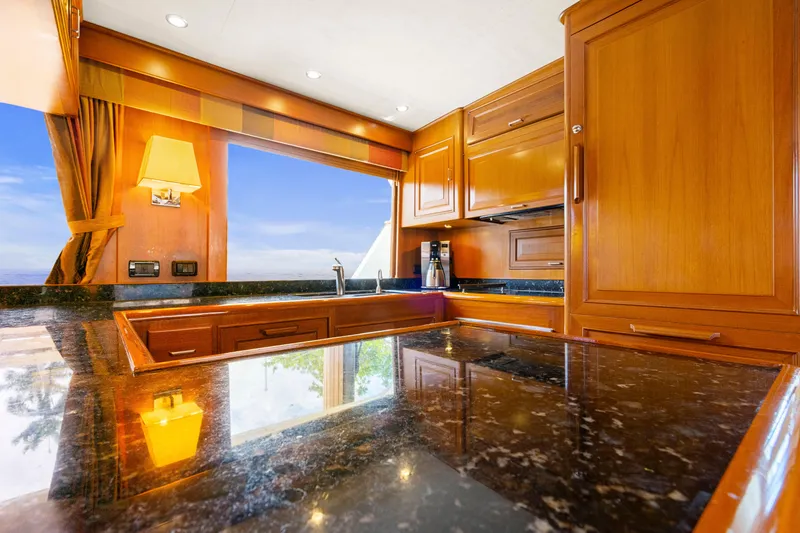 Slide: The Image of Luxurious kitchen interior on a 2006 Fleming 75 yacht with wooden cabinetry and granite countertops. - 9