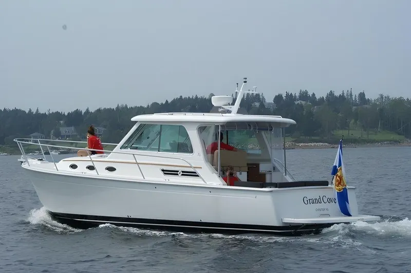 Slide: The Image of 2014 Back Cove 34 boat cruising on water with people onboard, displaying a flag. - 0