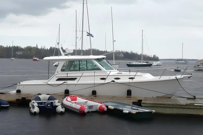 Slide: The Image of 2014 Back Cove 34 yacht docked with small boats nearby on a cloudy day. - 1