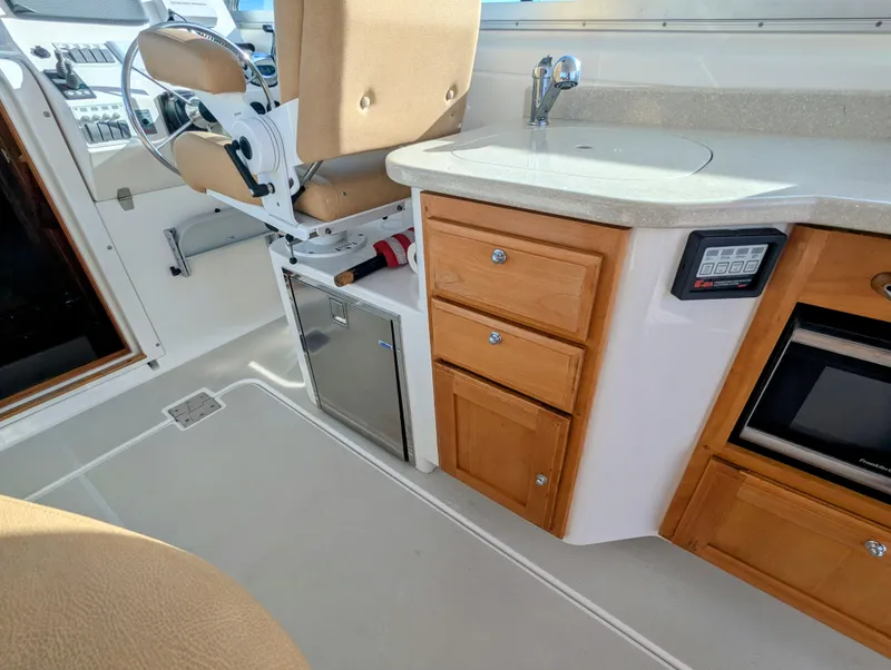 Slide: The Image of Interior of 2014 Back Cove 34 boat with helm seat, sink, and wooden cabinetry. - 10