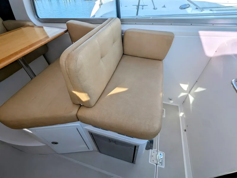Slide: The Image of 2014 Back Cove 34 interior with beige seating and wooden table, showcasing modern design. - 13