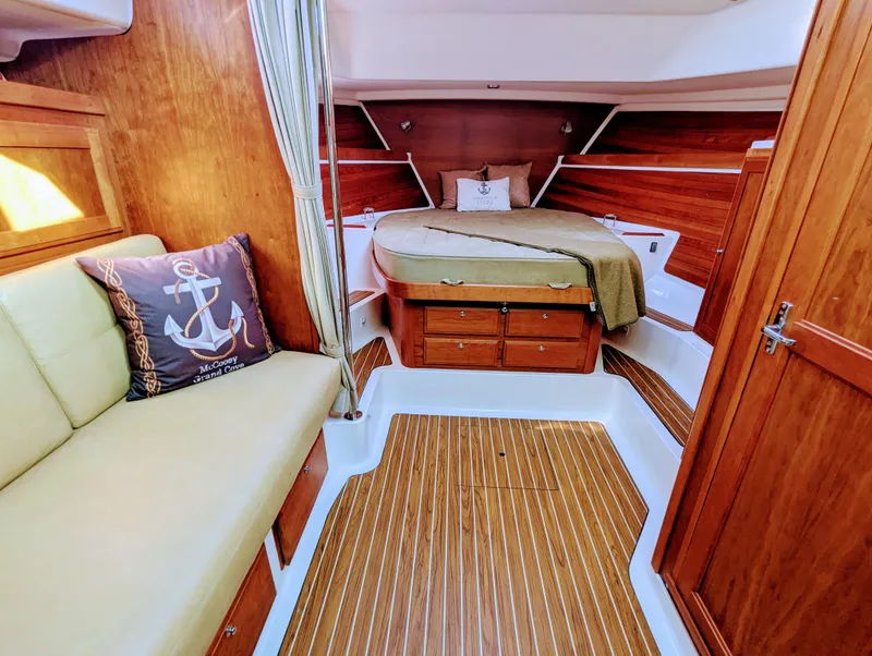 Slide: The Image of 2014 Back Cove 34 interior with wood finish, cozy bed, and nautical-themed decor. - 15