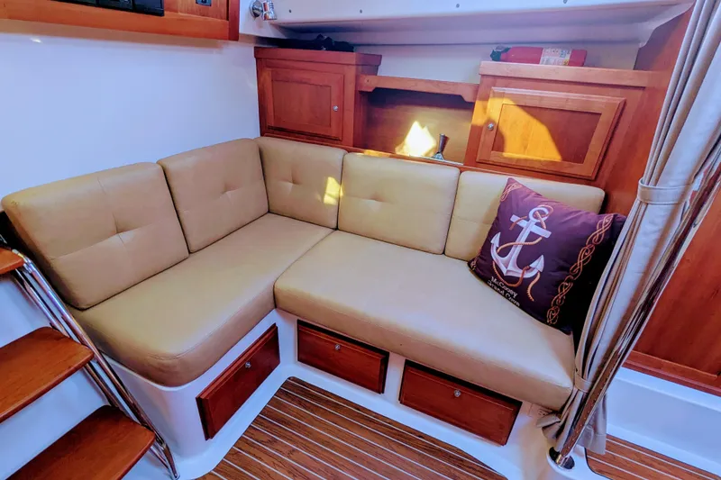 Slide: The Image of 2014 Back Cove 34 interior with beige L-shaped seating and nautical-themed decor. - 17
