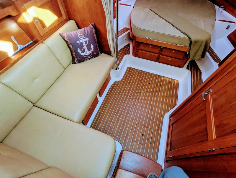 Slide: The Image of 2014 Back Cove 34 interior with beige seating, wooden flooring, and nautical-themed decor. - 18
