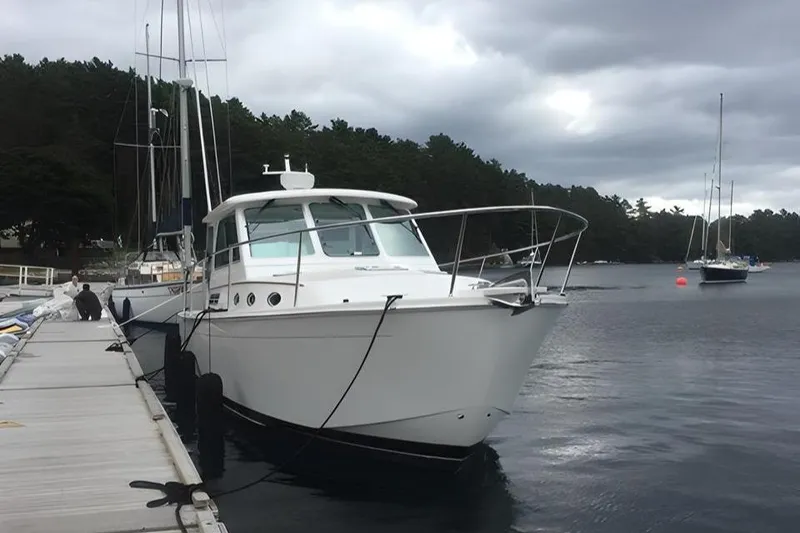 Slide: The Image of 2014 Back Cove 34 boat docked on a cloudy day, surrounded by calm waters. - 2