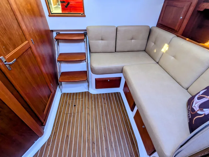 Slide: The Image of 2014 Back Cove 34 interior with beige seating, wooden flooring, and storage cabinets. - 20