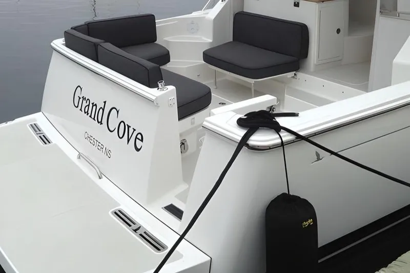 Slide: The Image of 2014 Back Cove 34 boat with seating, named "Grand Cove," docked at a marina. - 3
