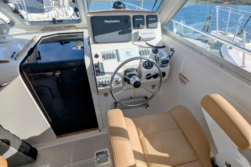Slide: The Image of 2014 Back Cove 34 helm with steering wheel, navigation controls, and beige seating. - 7