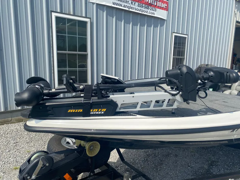 Slide: The Image of 2011 Triton 21 HP SC boat with Minn Kota trolling motor, parked outside a metal building. - 5