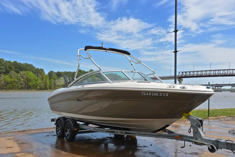 Slide: The Image of 2005 Sea Ray 220 Select boat on trailer by a lake with a bridge in the background. - 15