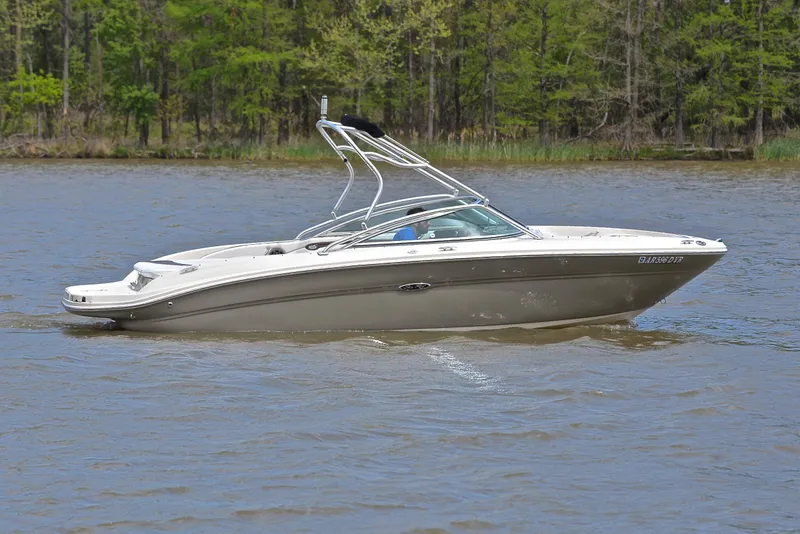 Slide: The Image of 2005 Sea Ray 220 Select boat cruising on a calm lake with forested shoreline. - 6