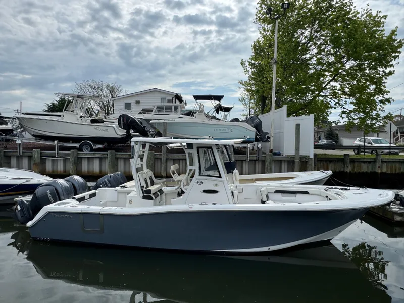 Slide: The Image of 2022 Tidewater 292 CC Adventure boat docked in a marina, overcast sky. - 1