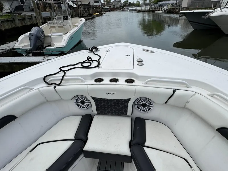 Slide: The Image of 2022 Tidewater 292 CC Adventure boat interior with seating and speakers, docked in a marina. - 21