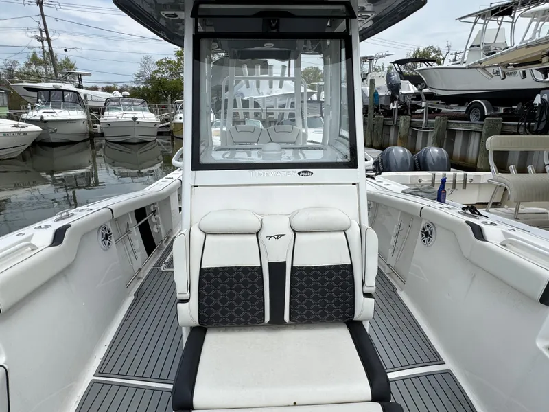 Slide: The Image of 2022 Tidewater 292 CC Adventure boat interior, featuring seating and helm, docked at a marina. - 23