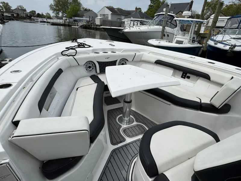 Slide: The Image of 2022 Tidewater 292 CC Adventure boat with spacious seating and table in a marina setting. - 26
