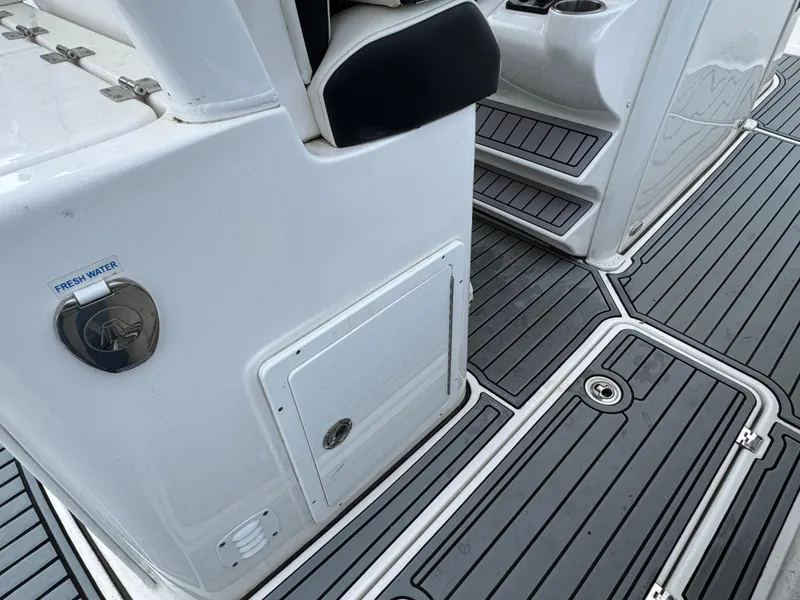 Slide: The Image of 2022 Tidewater 292 CC Adventure boat interior with sleek gray decking and fresh water access. - 9