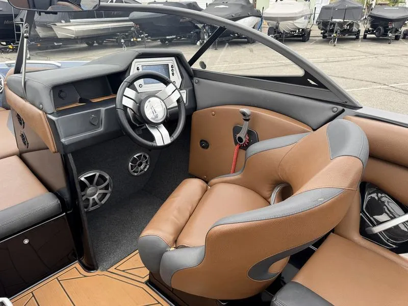 Slide: The Image of 2018 Tigé R21 boat interior with brown and gray seating, modern dashboard, and steering wheel. - 11