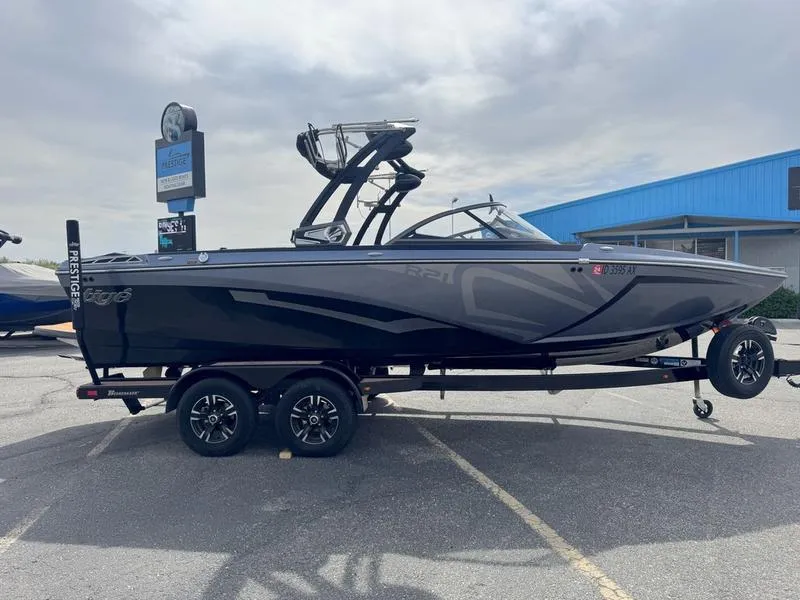 Slide: The Image of 2018 Tigé R21 boat on trailer, parked outdoors, with a blue building in the background. - 7