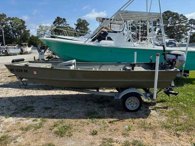 Slide: The Image of 2016 Crestliner CR 1448T boat on trailer, parked outdoors near larger boats. - 2