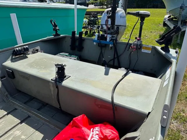 Slide: The Image of 2016 Crestliner CR 1448T boat interior with motor and equipment, parked on grass. - 8