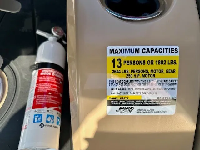 Slide: The Image of 2025 Barletta C24UE boat capacity label, 13 persons or 1892 lbs, with fire extinguisher nearby. - 11