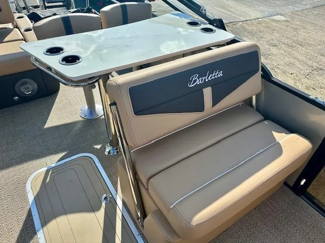 Slide: The Image of 2025 Barletta C24UE boat interior with beige seating and a table with cup holders. - 3