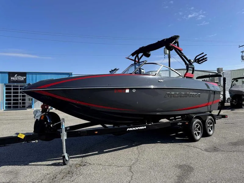Slide: The Image of 2021 Moomba Craz boat on trailer, sleek design, black and red accents, parked outdoors. - 2